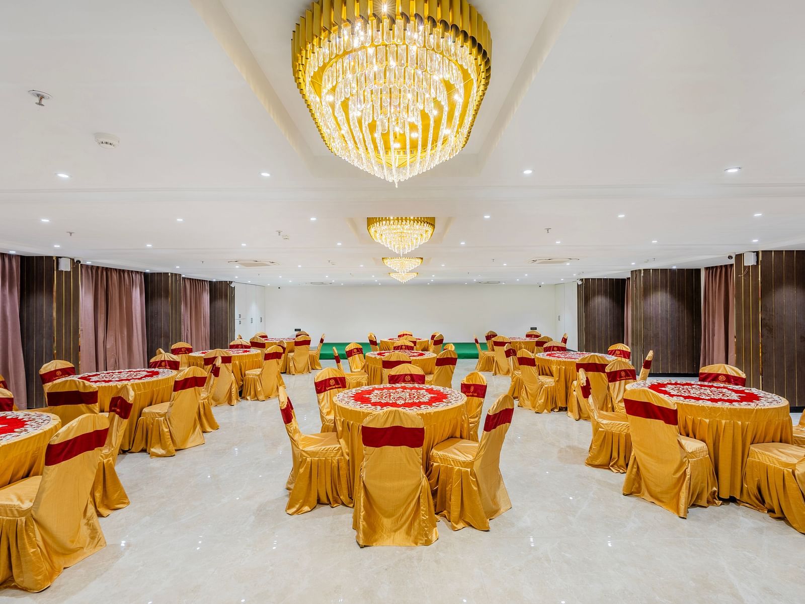 Lemonridge Hotels, KPHB | Banquet hall with round dining tables and chairs, featuring a unique ceiling light.